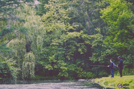 Young men fishing at river in forestの写真素材