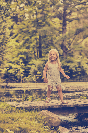 Portrait of happy girl standing on wooden bridgeの写真素材