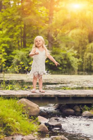 Portrait of cute little girl standing on wooden bridgeの写真素材