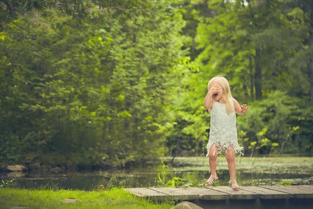 Little girl covering face and crying on bridgeの写真素材