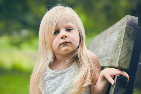 Portrait of displeased little girl sitting on benchの写真素材