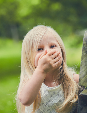 Funny little girl laughing covering mouthの写真素材