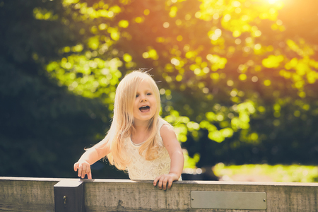 Excited little girl standing on bench in parkの写真素材