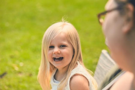 Little girl laughing sitting at her motherの写真素材