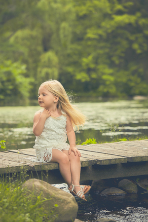 Portrait of smiling little girl sitting on bridgeの写真素材