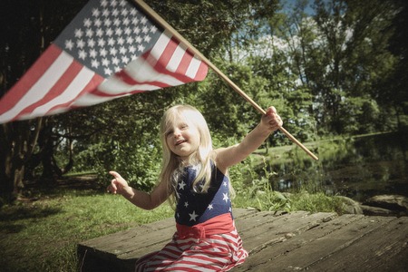 Positive little girl waving American flagの写真素材
