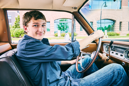 Portrait of happy young Caucasian man driving his car, looking at camera and smilingの写真素材