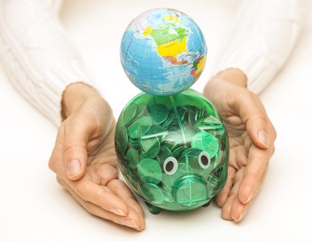 Female hands hold the Globe and piggy bank. Global finance conceptの写真素材