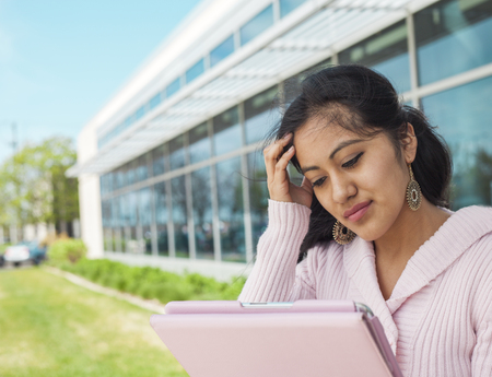 Student failed exam. Stressful girl touching her and holding tablet outsideの写真素材