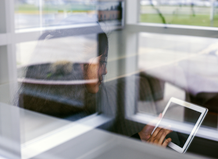 View through window of businesswoman looking at tabletの写真素材