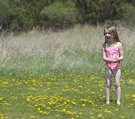Beautiful happy girl playing with sprinkle water outsideの写真素材