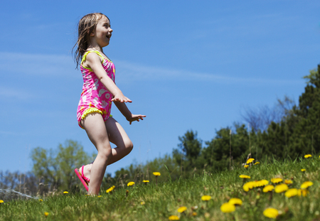 Joyful girl playing with sprinkle water outside and having fun. Summer conceptの写真素材