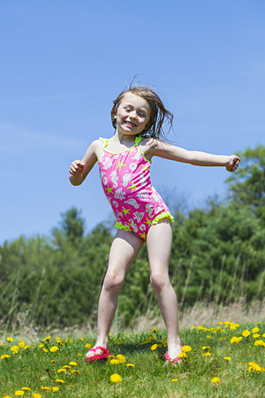 Joyful girl playing with sprinkle water outside and having funの写真素材