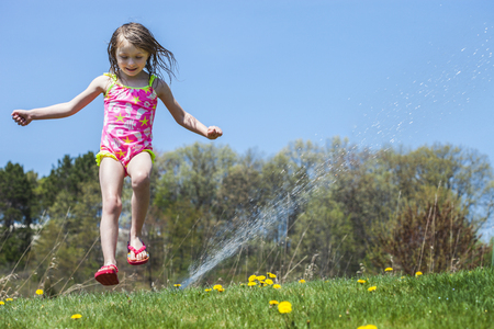 Joyful girl playing with sprinkle water outside and having fun. Summer conceptの写真素材