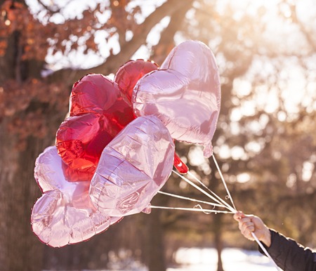 Male hand holding heart balloons. Valentines day conceptの写真素材