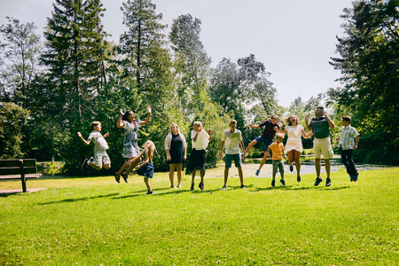 Happy family of eleven jumping in summer parkの写真素材