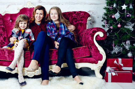 Portrait of happy woman with two daughters sitting on sofaの写真素材