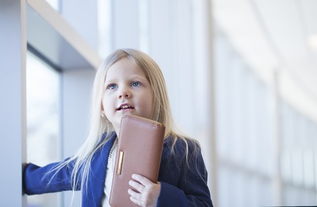 Face of smiling little girl wearing blue jacket holding walletの写真素材