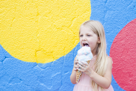 Beautiful blond girl holding ice-cream on colorful backgroundの写真素材