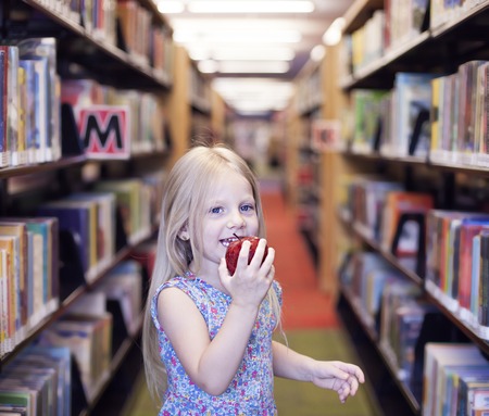 Happy schoolgirl apple and eating it. Knowledge or wisdom conceptの写真素材