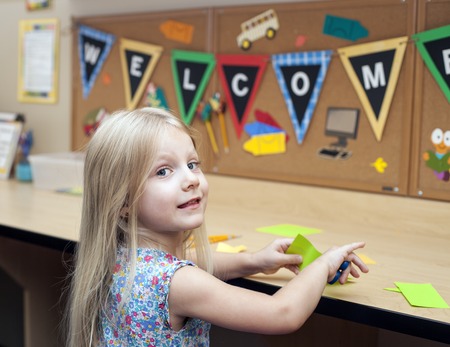 Smart happy girl cutting paper, making craft, Welcome back to schoolの写真素材