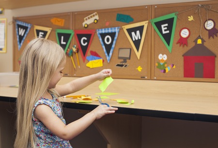 Smart happy girl cutting paper, making craft, Welcome back to school