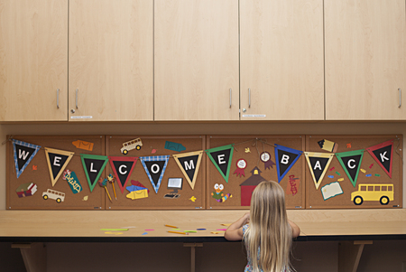 Smart happy girl cutting paper, making craft, Welcome back to schoolの写真素材