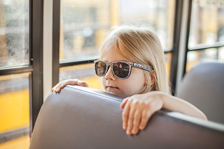 Schoolgirl sitting in school bus and ready for her first rideの写真素材