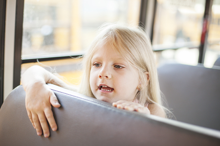 Schoolgirl sitting in school bus and ready for her first rideの写真素材