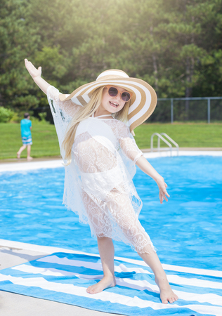 Happy little girl with hat next to public swimming poolの写真素材