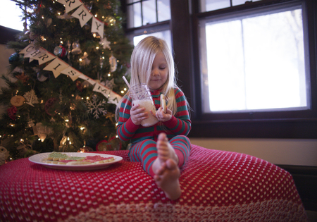Cheerful girl in pajama eating cookies. Christmas timeの写真素材