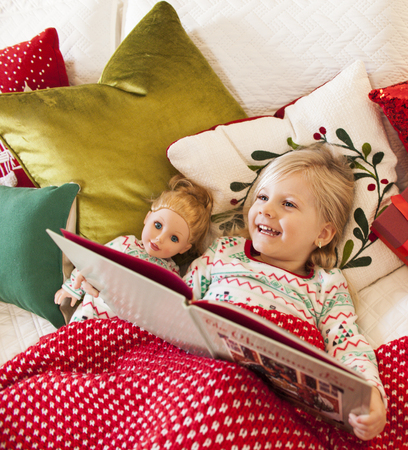 Happy girl reading book in bed- Christmas timeの写真素材