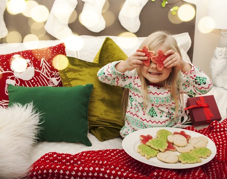 Joyful girl in bed holding cookies for santa claus - Christmas timeの写真素材