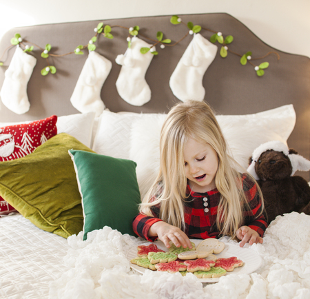 Joyful girl in bed holding cookies for santa claus - Christmas timeの写真素材