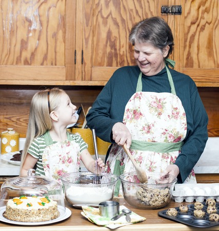 Happy grandmother and granddaughter cooking together and having fun in the kitchenの写真素材