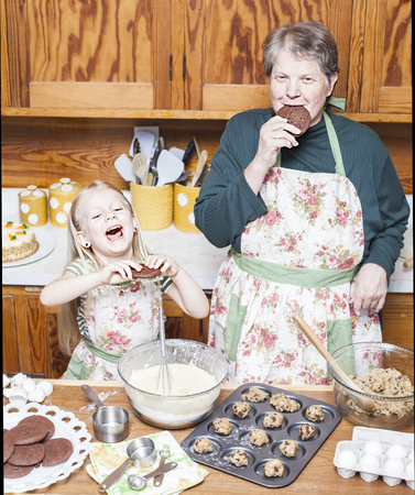 Happy grandmother and granddaughter cooking together and having fun in the kitchenの写真素材
