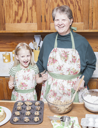 Happy grandmother and granddaughter cooking together and having fun in the kitchenの写真素材