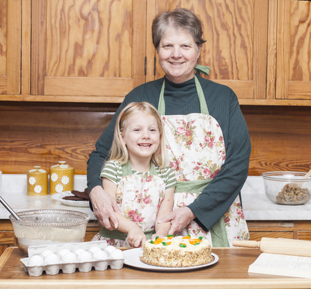 Happy grandmother and granddaughter cooking together and having fun in the kitchenの写真素材