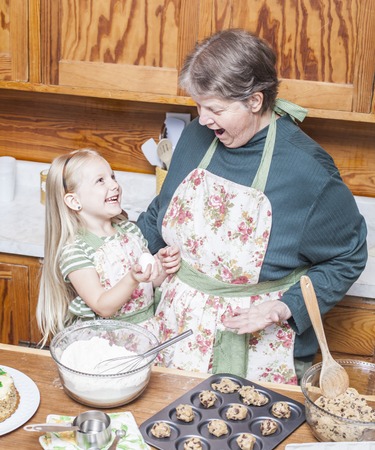 Happy grandmother and granddaughter cooking together and having fun in the kitchenの写真素材