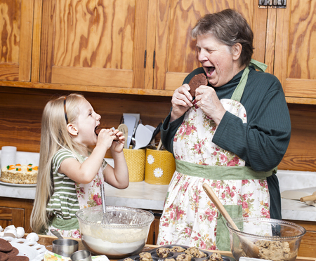 Happy grandmother and granddaughter cooking together and having fun in the kitchenの写真素材