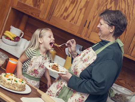 Happy grandmother and granddaughter cooking together and having fun in the kitchenの写真素材