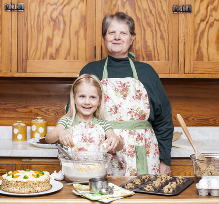 Happy grandmother and granddaughter cooking together and having fun in the kitchenの写真素材