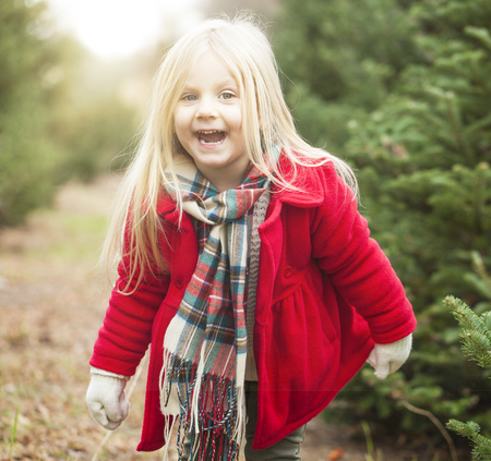 Happy little girl jumping in fir tree farm. Playful time. Happiness conceptの写真素材