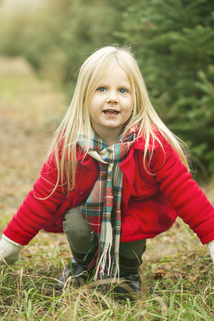 Happy little girl jumping in fir tree farm. Playful time. Happiness conceptの写真素材
