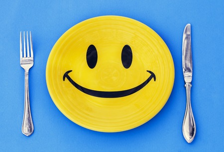 Yellow plate with smile and cutlery on blue backgroundの写真素材