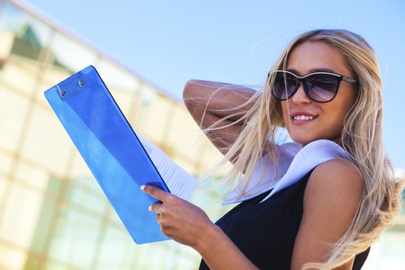 Successful business woman in sunglasses next to modern buildingの写真素材