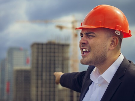 Worker engineer in helmet pointing at construction. Labor dayの写真素材