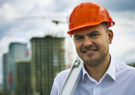 Happy worker builder in hardhat with level on the background of constructionの写真素材