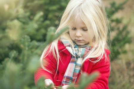 Close-up of serious little girl walking in forest. Face of cute girl wearing red coat and scarfの写真素材