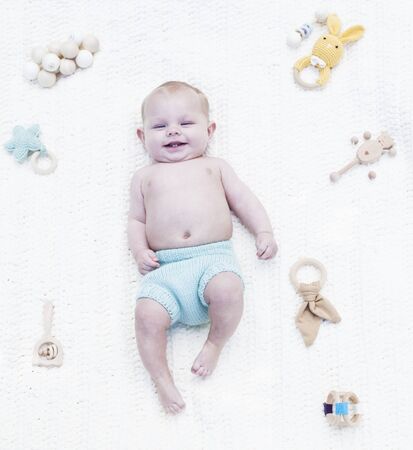 Smiling little baby sleeping on blanket with toys. Portrait of happy baby boy in blue diaper lying in cradle. Newborn child, childhood, healthy childの写真素材